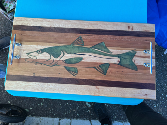 Wooden cutting board with fish design on a blue surface